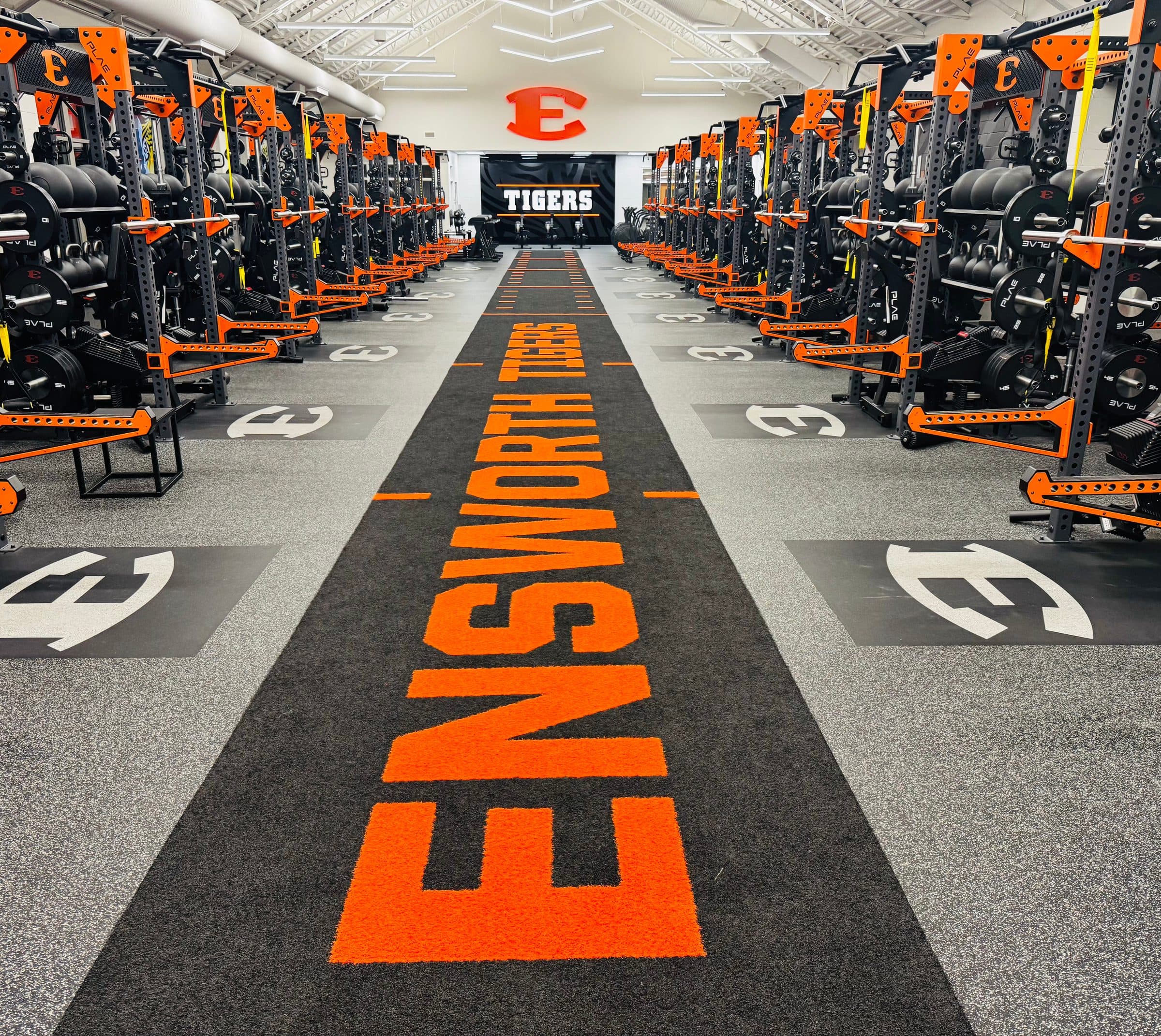 Rows of matched racks down both sides of a high school weight room