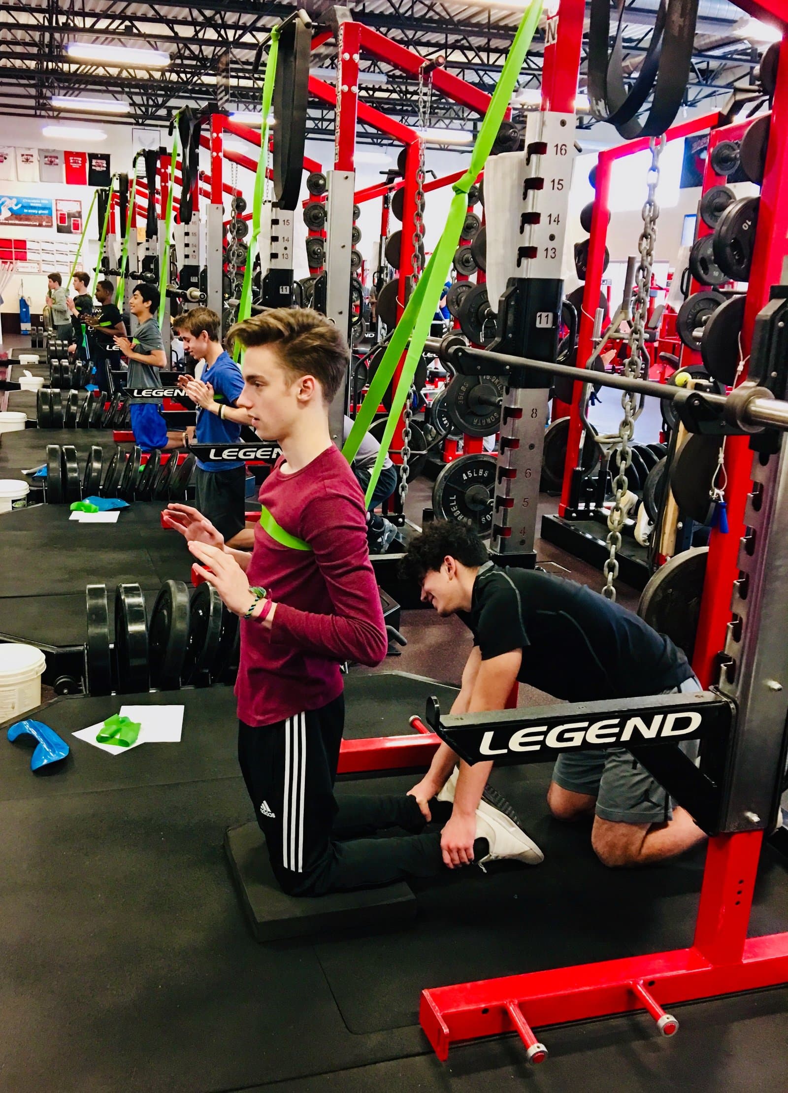 Athletes working through a banded movement at the racks while a teammate holds position