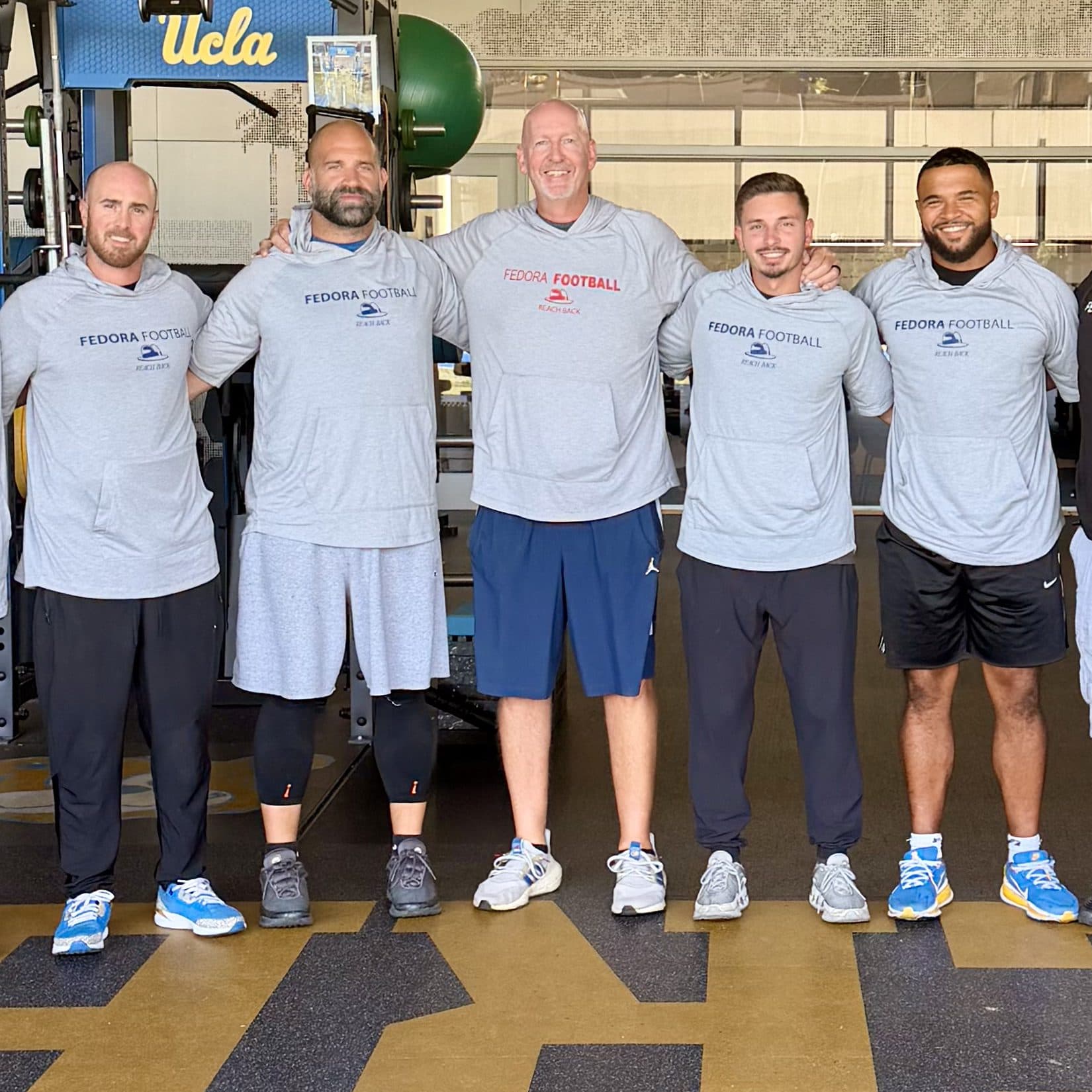 Coach Martens with a group of coaches in the UCLA football weight room